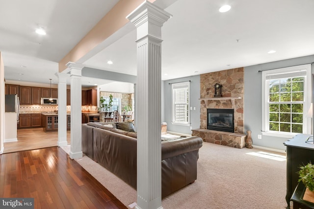 living room featuring decorative columns, a fireplace, baseboards, recessed lighting, and hardwood / wood-style flooring