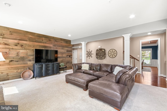 carpeted living room featuring wooden walls, recessed lighting, baseboards, decorative columns, and wood finished floors