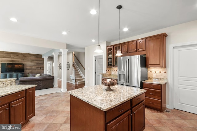 kitchen featuring decorative backsplash, glass insert cabinets, open floor plan, stainless steel refrigerator with ice dispenser, and a center island