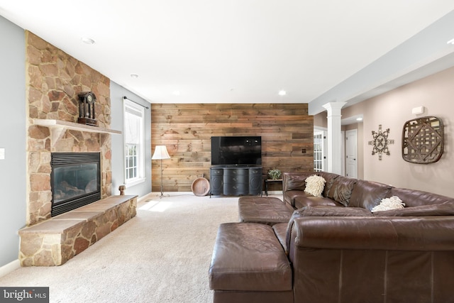 living room featuring wood walls, decorative columns, a fireplace, baseboards, and carpet flooring