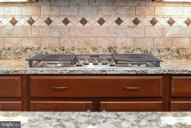 room details featuring light stone counters, stainless steel gas stovetop, and tasteful backsplash