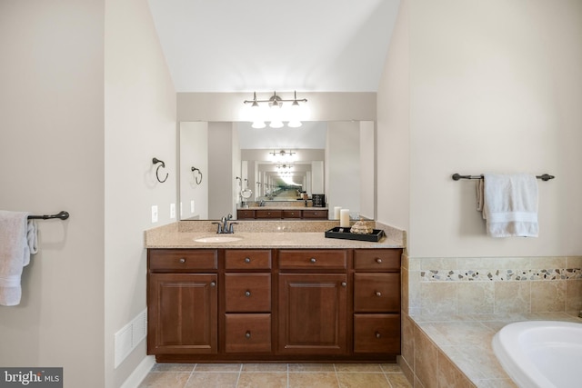 full bathroom with vanity, a relaxing tiled tub, and visible vents