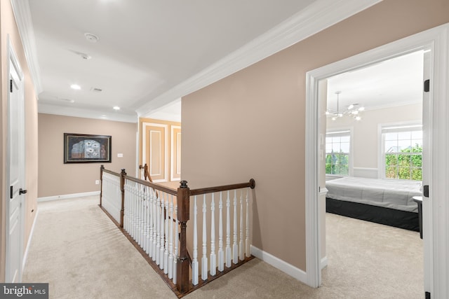 hallway with carpet floors, ornamental molding, baseboards, and an upstairs landing