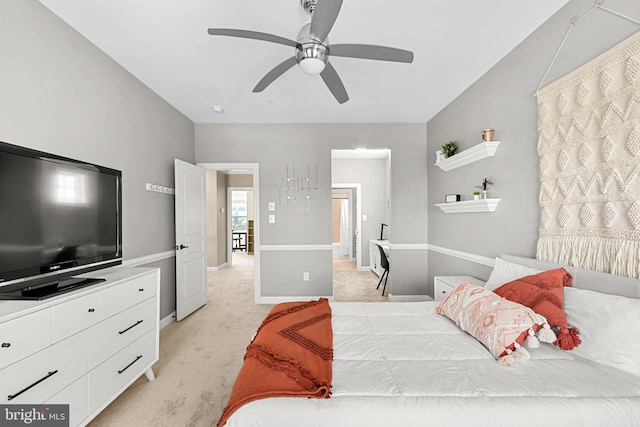 bedroom featuring baseboards, light carpet, a ceiling fan, and ensuite bath