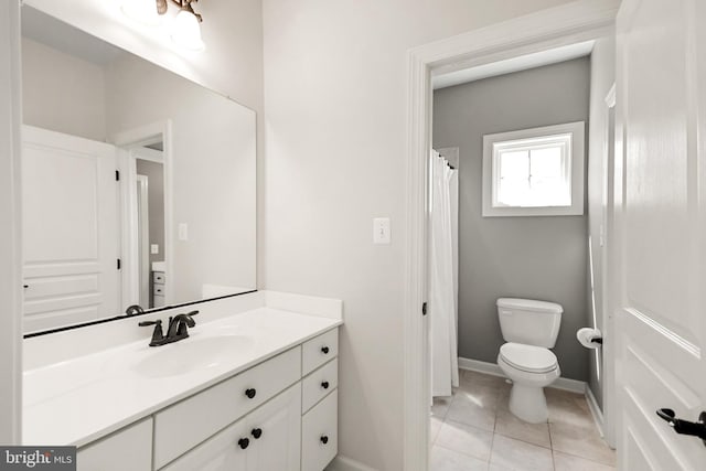 bathroom with vanity, baseboards, tile patterned flooring, and toilet