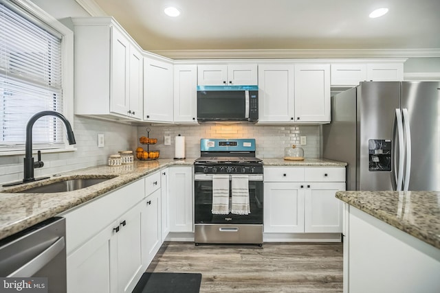 32 Meadowlark Ln, Willingboro, NJ 08046 - kitchen with light wood-type flooring, white cabinetry, tasteful backsplash, a sink, and stainless steel appliances