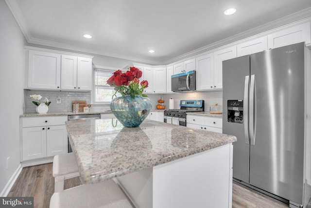 32 Meadowlark Ln, Willingboro, NJ 08046 - kitchen featuring white cabinets, appliances with stainless steel finishes, ornamental molding, and light wood-type flooring