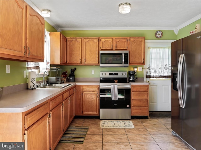 kitchen featuring crown molding, light tile patterned flooring, light countertops, a sink, and stainless steel appliances