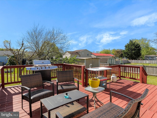 deck with a residential view, a storage shed, area for grilling, a fenced backyard, and an outbuilding
