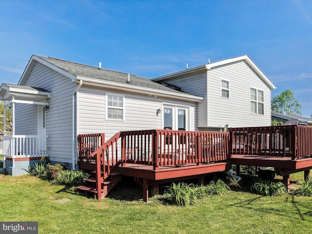 rear view of property featuring a lawn, a shingled roof, and a deck
