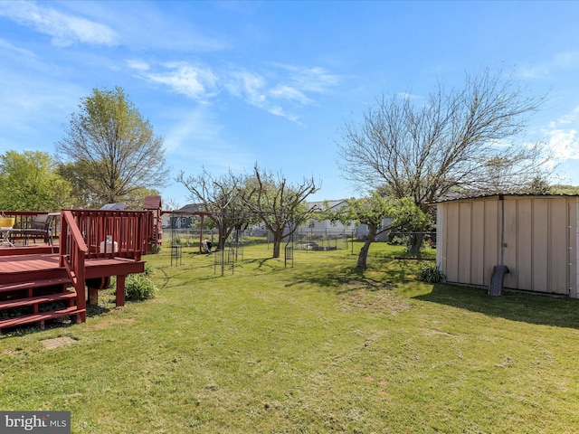 view of yard featuring a deck, fence, an outbuilding, and a shed