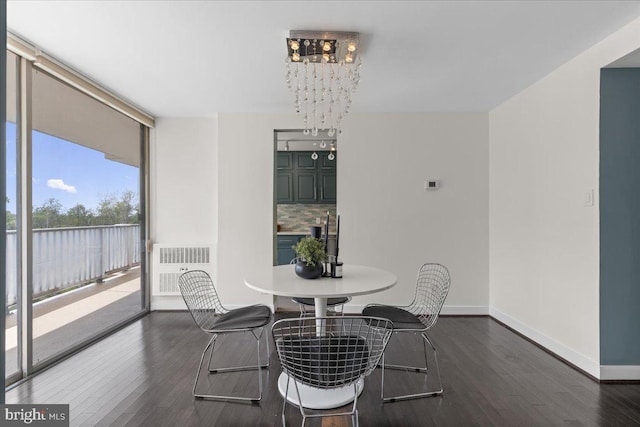 dining space with dark wood-style flooring, floor to ceiling windows, a chandelier, and baseboards