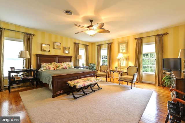 bedroom featuring visible vents, wallpapered walls, and wood finished floors