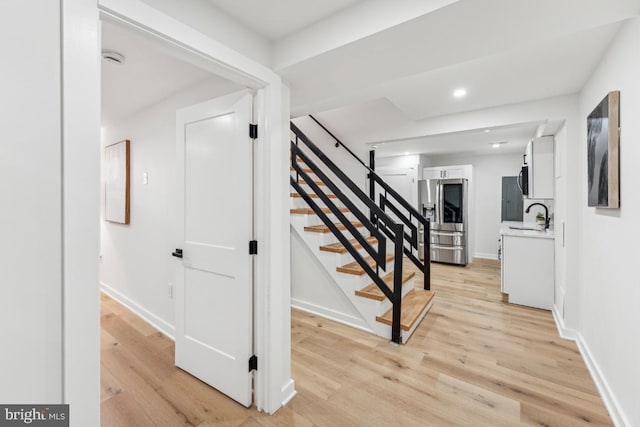 stairway with wood finished floors, recessed lighting, and baseboards