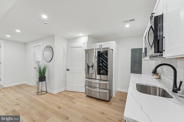 kitchen with light stone countertops, a sink, stainless steel appliances, visible vents, and white cabinets