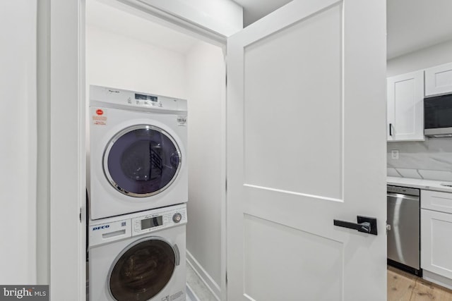 laundry room featuring stacked washing maching and dryer, light wood-type flooring, and laundry area