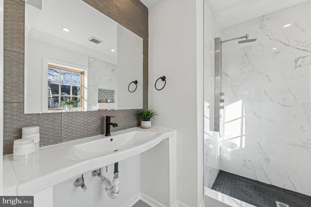 bathroom with a sink, visible vents, a marble finish shower, and recessed lighting