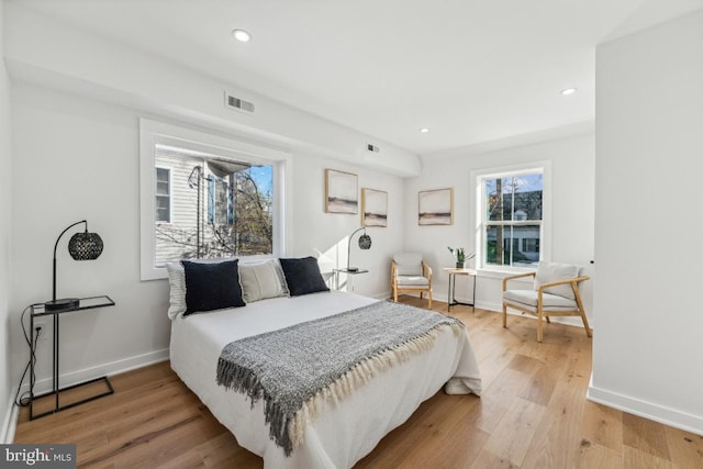 bedroom featuring light wood-style floors, baseboards, visible vents, and multiple windows