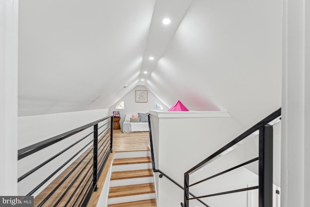 staircase featuring wood finished floors, recessed lighting, and vaulted ceiling