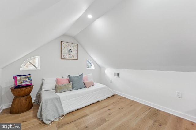bedroom featuring baseboards, visible vents, wood finished floors, and lofted ceiling