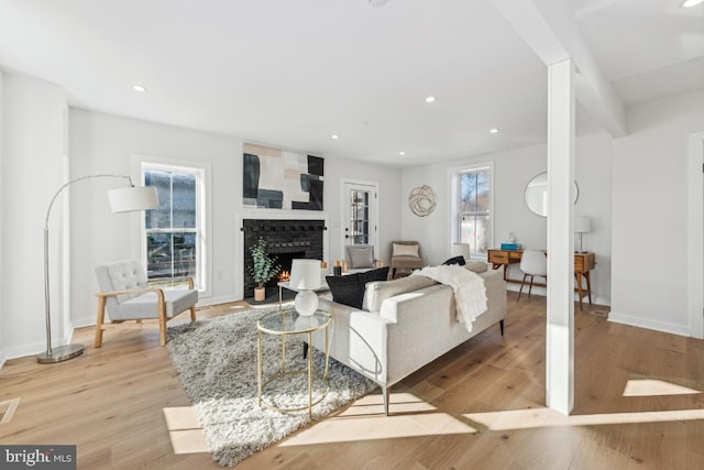 living area featuring a fireplace, light wood-style floors, visible vents, and baseboards