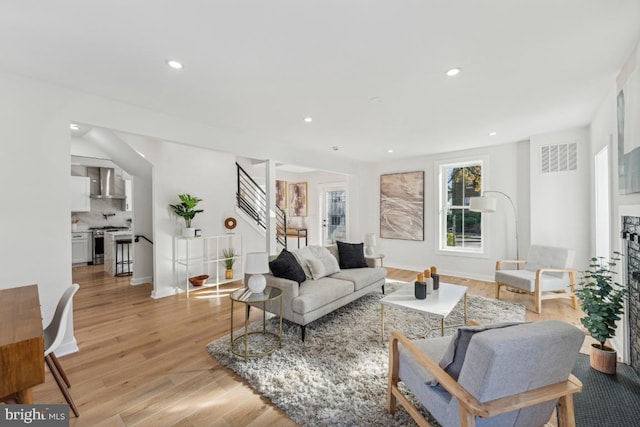 living area featuring visible vents, light wood-type flooring, stairs, and recessed lighting