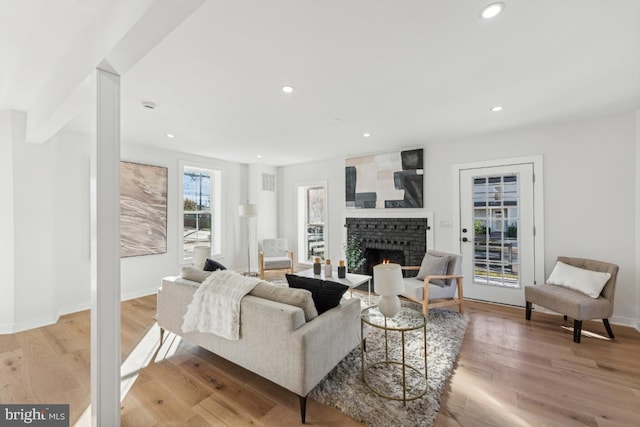 living room with a fireplace, recessed lighting, and light wood finished floors