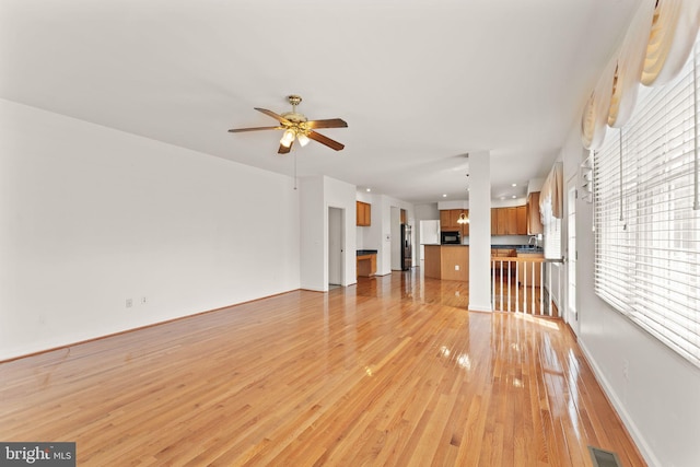 42935 Palliser Ct, Leesburg, VA 20176 - unfurnished living room featuring ceiling fan, baseboards, and light wood-style floors