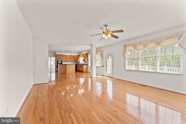 42935 Palliser Ct, Leesburg, VA 20176 - unfurnished living room with a ceiling fan, a healthy amount of sunlight, baseboards, and light wood-style floors