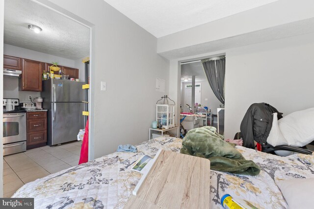 bedroom featuring freestanding refrigerator and light tile patterned floors