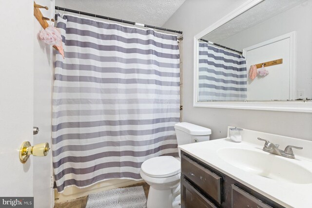full bathroom featuring vanity, a textured ceiling, and toilet