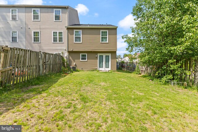 rear view of house with a yard, french doors, and a fenced backyard