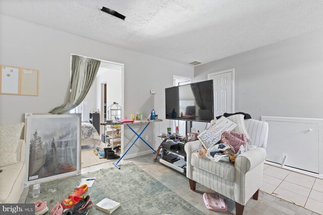 living area featuring tile patterned flooring, a textured ceiling, and visible vents