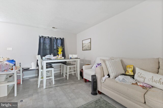 living room featuring visible vents, a textured ceiling, and baseboards