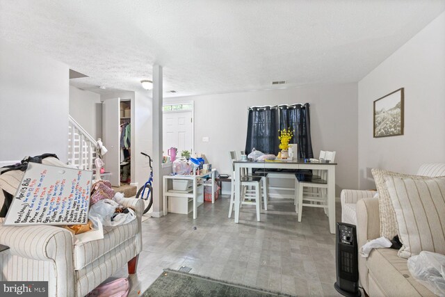 living area featuring stairs, a textured ceiling, and visible vents