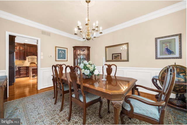 dining space with visible vents, crown molding, a notable chandelier, and dark wood-style floors