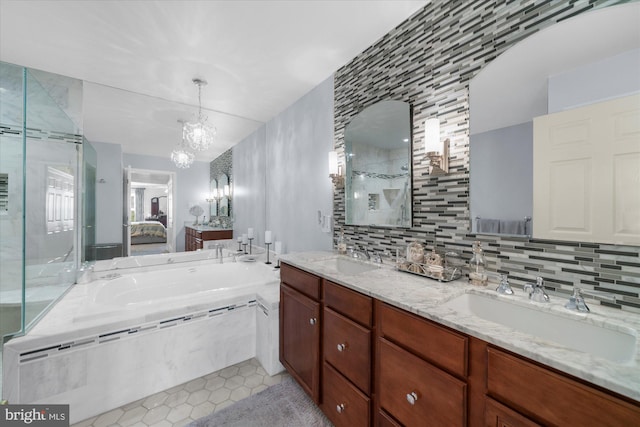 ensuite bathroom with an inviting chandelier, a tile shower, tile patterned floors, and a sink