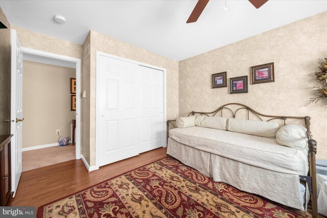 bedroom featuring baseboards, wood finished floors, a ceiling fan, and a closet