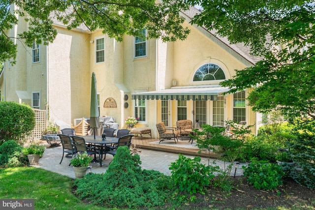 back of property with a patio and stucco siding