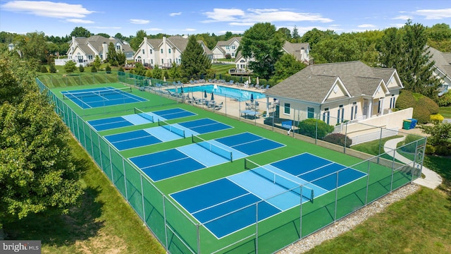 exterior space featuring a tennis court, fence, and a residential view