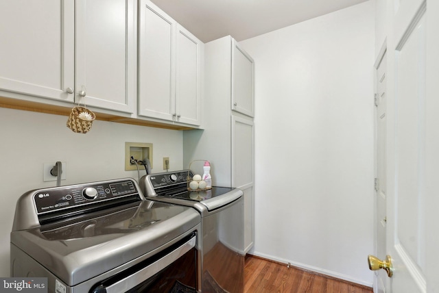 laundry room with wood finished floors, washer and dryer, cabinet space, and baseboards