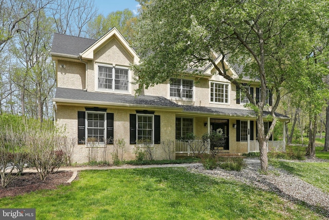 view of front of property featuring stucco siding, covered porch, and a front yard