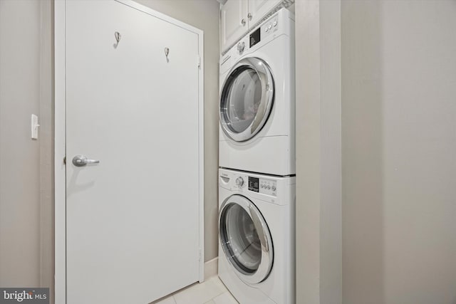 laundry area with estacked washer and dryer and light tile patterned flooring