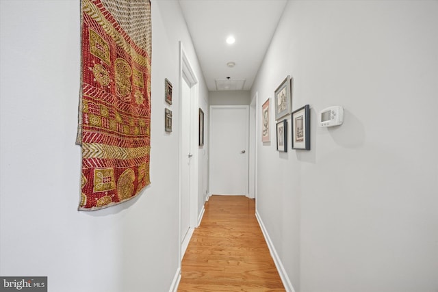 corridor featuring attic access, light wood-style floors, baseboards, and recessed lighting