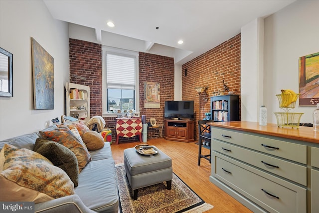 living area featuring brick wall and light wood-style flooring