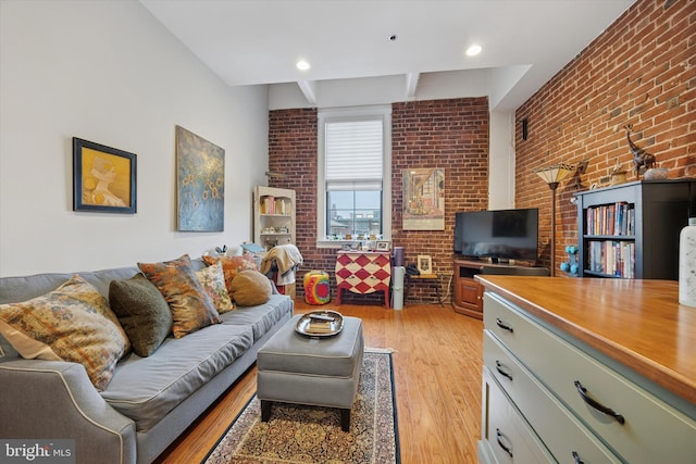 living room with brick wall, light wood-type flooring, and beam ceiling