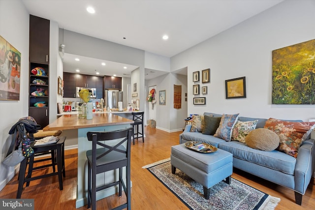 living room featuring light wood-style flooring, recessed lighting, and baseboards