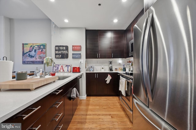 kitchen with appliances with stainless steel finishes, light wood finished floors, light countertops, recessed lighting, and dark brown cabinetry