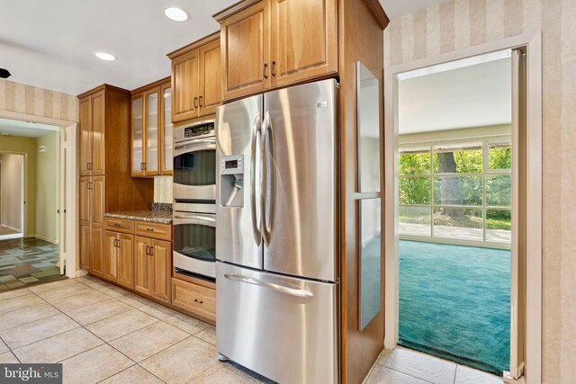 kitchen with appliances with stainless steel finishes, brown cabinets, and wallpapered walls