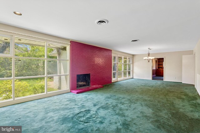 unfurnished living room featuring carpet floors, a brick fireplace, a notable chandelier, and a healthy amount of sunlight